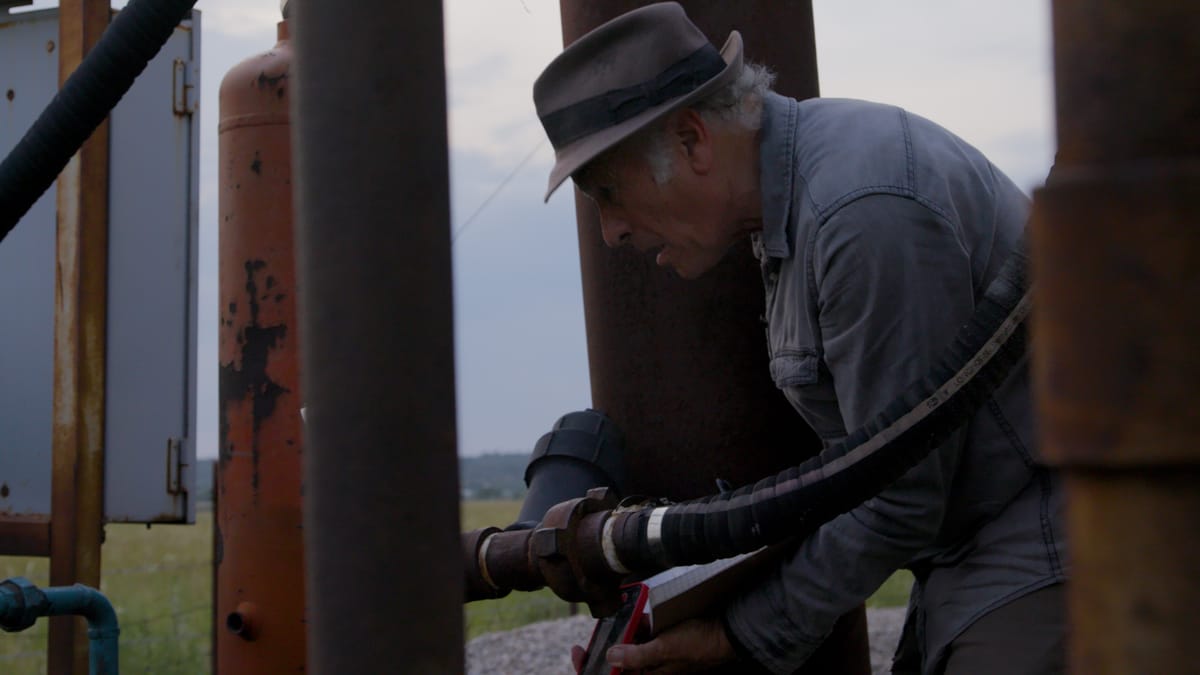 Greg Palast inspecting oil-well piping in the field.